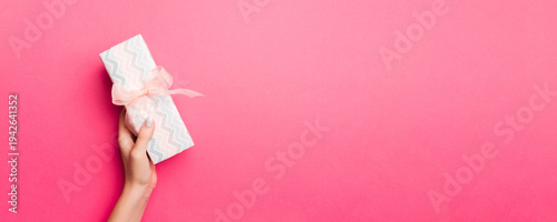 Wallpaper Mural Girl Hands holding craft paper gift box with as a present for Christmas or other holiday on pink background, top view with copy sppace Torontodigital.ca