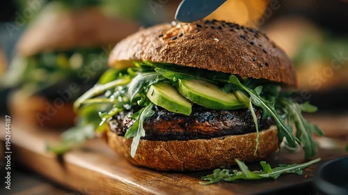 Delicious gourmet burger with fresh avocado and arugula on a rustic wooden board capturing textures and colors with soft focus background