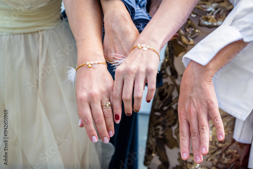 Obraz na plátně Closeup of four women hands showing matching bracelets and manicure during wedding celebration