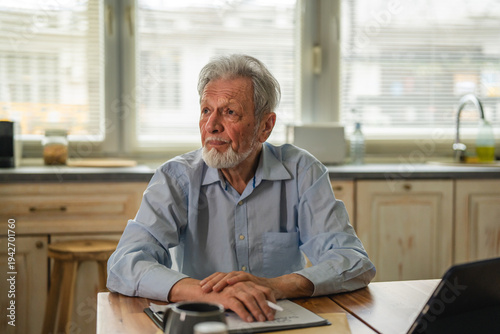 Schilderij op canvas Senior man concentrating on paperwork and digital tablet at home table