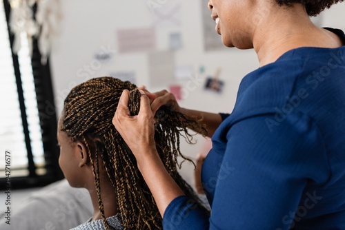 Photography Woman braiding young girl's hair.