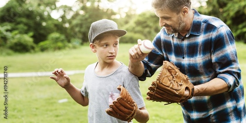 Photography A man teaches a boy baseball in a park