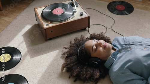 Young african woman listening analog music with vintage vinyl disk at home - Model by AI generative