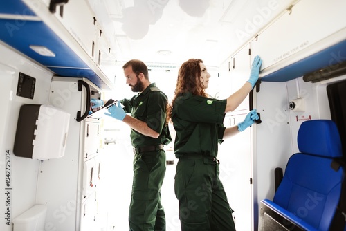 Cuadro en lienzo Two paramedics in green uniforms organize equipment inside an ambulance