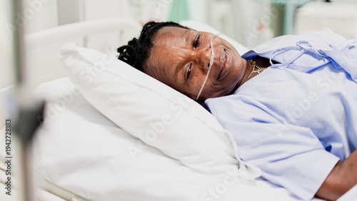 Tableau sur toile A person lying in a hospital bed, wearing a nasal cannula, smiling gently