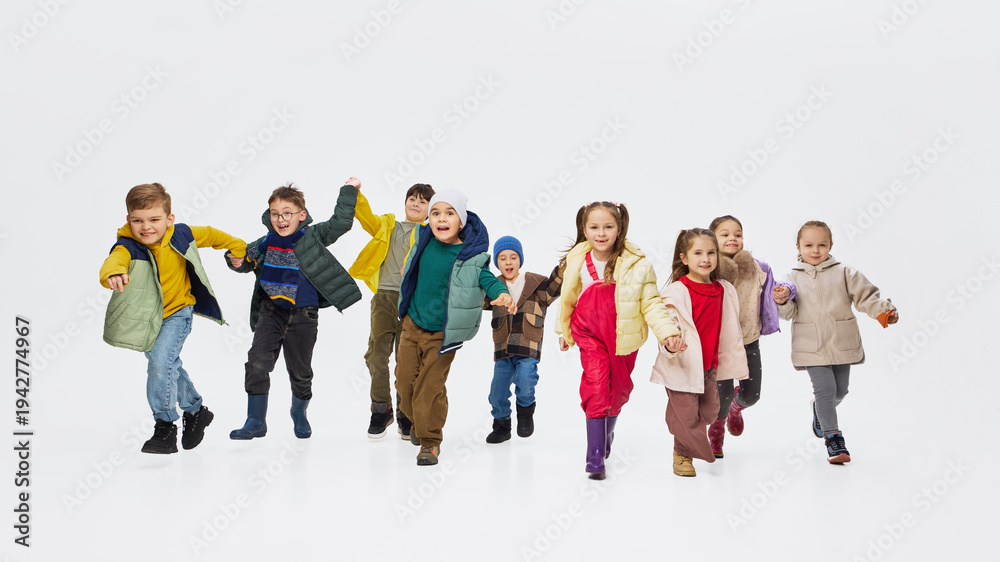 Obraz premium Children running toward camera wearing colorful kids outfits in studio. Concept of playful childhood movement, modern kids clothing and energetic fashion campaign.