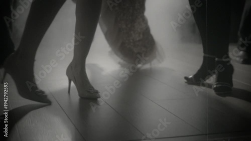 1920s old style black and white color group of people close-up legs body part dancing crowd in dark night club. girls flapper female male have fun at dance floor birthday party retro roaring twenties