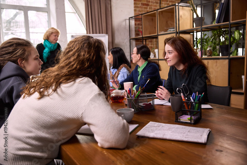 Foto Young women discussing ideas at modern workspace table