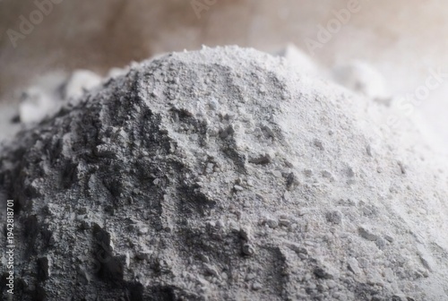 A pile of gray cement or concrete dust. It appears to be being poured or spread. A construction site or workshop.