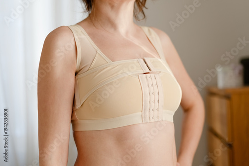 A close-up of a woman after mammoplasty wearing a support bra and post-operative corset. Post-surgery rehabilitation, support for women after breast cancer.