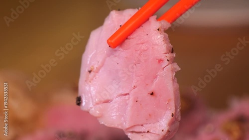 Pink piece of sous vide sirloin picked up with chopsticks