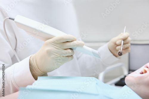 Fotografie Dentist holds portable 3D scanner in his hand to examine the jaw and oral cavity
