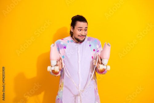 Konstfotografi Playful man in pastel pajama jumpsuit holds pink roller skates on bright yellow