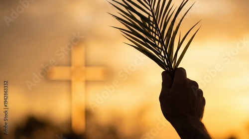 Hand holding palm leaf against blurred Christian cross at sunset. Palm Sunday religious celebration. Worship service and faith concept. Symbol of victory and peace in Christianity.