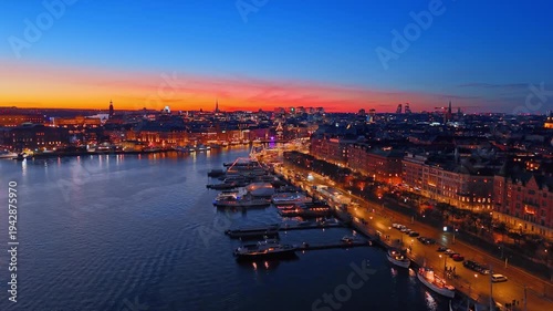 Beautiful illuminated quay with boats standing along, long promenade and highway, lined with park. Fantastic lights of Stockholm, Sweden in the evening. Aerial view.