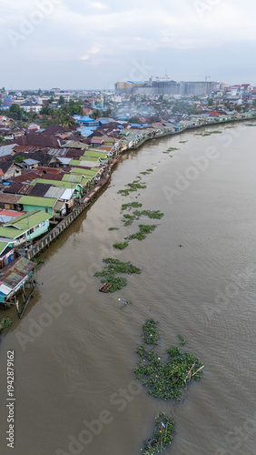 Aerial shot of a green village on the banks of the river in Banjarmasin, South Kalimantan in the afternoon
