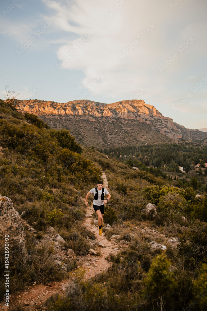 Obraz premium Athlete navigating a technical mountain trail while running through rugged natural terrain. Outdoor workout combining endurance, agility and adventure in wild landscape.