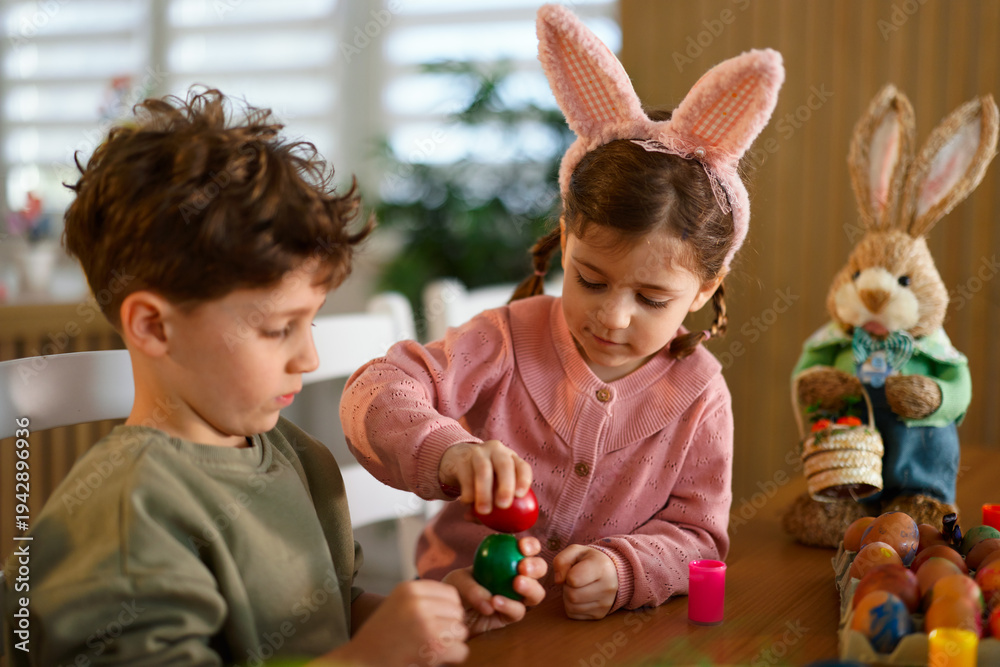 Naklejka premium Kids decorating colorful easter eggs at home