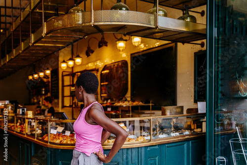 Independent Black woman standing with back turned in stylish cafe interior