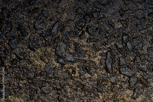 Wet rocky ground texture with dark stones and mud after rain, natural rough surface background