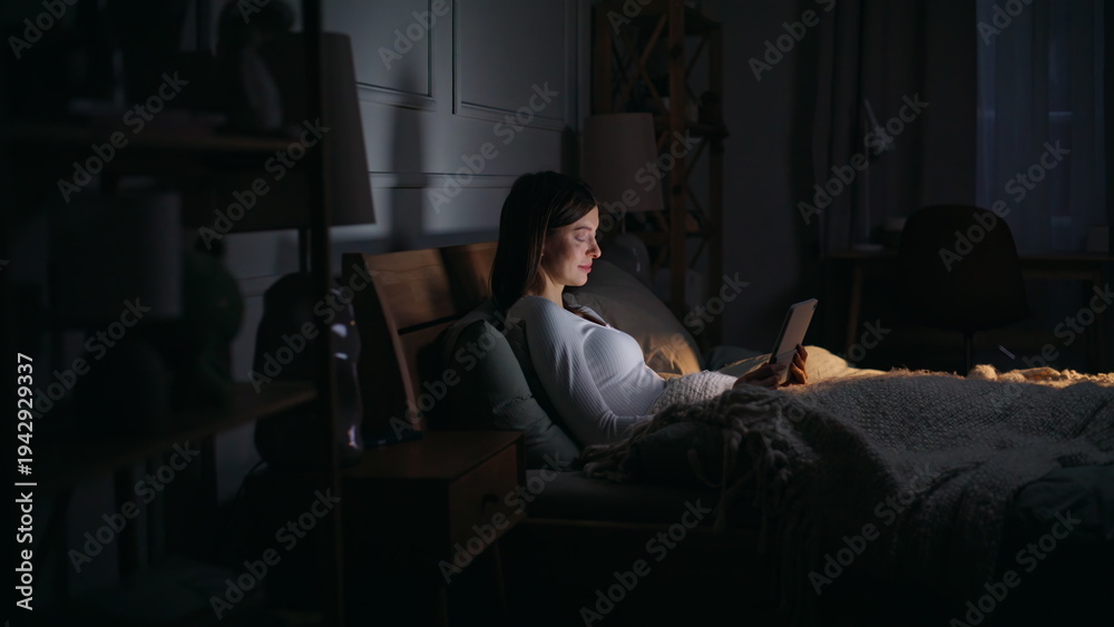 Fototapeta premium Lady surfing internet bedtime lying cozy dark bedroom. Freelancer reading email