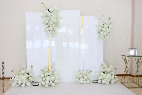 Photography Elegant wedding photo zone with white panels, gold accents and floral arrangements of white roses prepared for ceremony or celebration hall