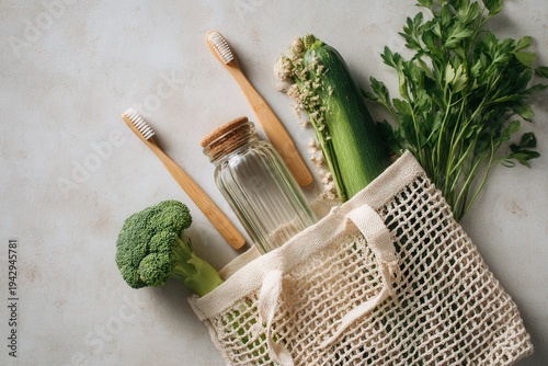 A flat lay of an eco-friendly lifestyle scene featuring a reusable shopping bag filled with fresh vegetables, a glass jar, and bamboo toothbrushes