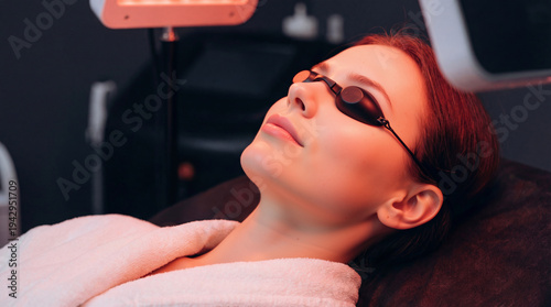 Wallpaper Mural Woman relaxing during red light therapy treatment. Female patient wearing protective goggles under LED panel in spa clinic. Advanced facial skincare procedure Torontodigital.ca