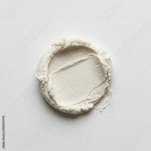 High-angle view of creamy white cosmetic texture stroke on white background