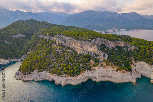 Aerial drone view of rocky Mediterranean coastline with cliffs and pine forest near Kemer Turkey
