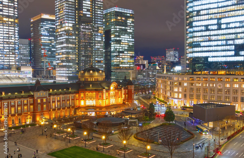 Bild auf Leinwand Illuminated Tokyo Station at night with historic red brick architecture and modern skyscrapers