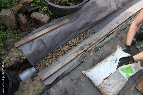 Garden drainage pipe system in gravel trench, underground water drainage installation. Underground drainage system used to remove excess rainwater and protect soil and landscaping from flooding.