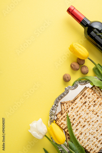 Happy Passover styled vertical still life featuring matzah, a wine bottle, tulip and walnut on a yellow background evoking spring tradition and festive ritual