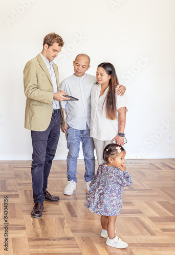 Toddler exploring preschool while parents talk with teacher during school admission visit