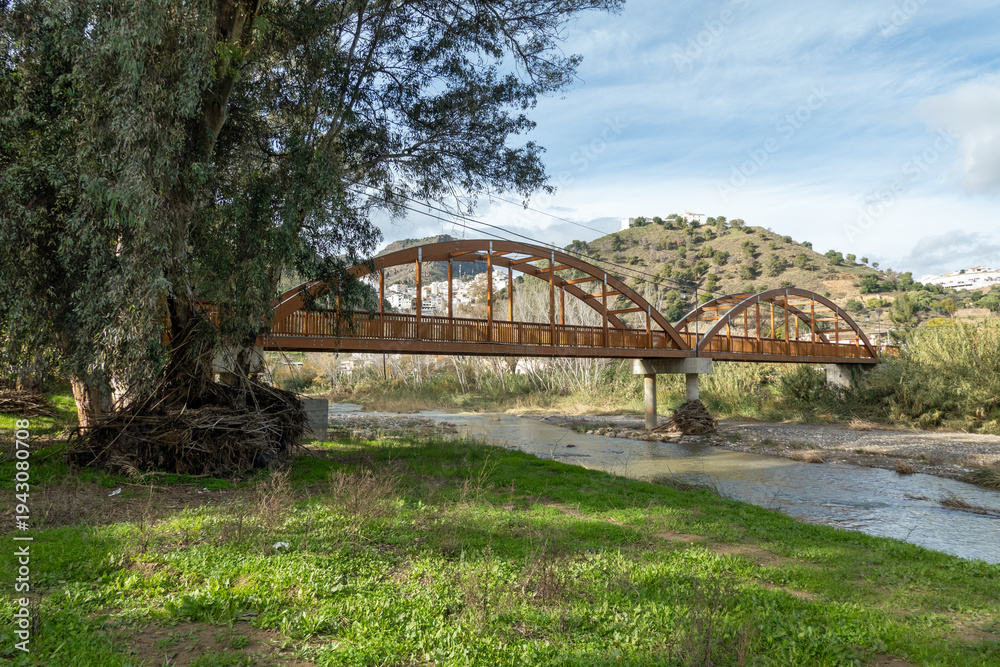 Obraz premium Pedestrian bridge (tied arch) crossing the Guadalhorce river near Alora in Andalusia, Spain; the river is low but ihas a history of sudden floods. 