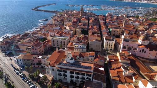 Alghero old town aerial view with Bell Tower and Cathedral dome over marina with yachts Sardinia Italy Mediterranean coast historic city architecture drone footage 4k travel destination