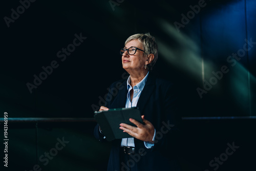 Photos Side portrait of senior woman using tablet with confident smile