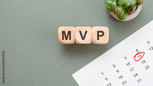 MVP Minimum Viable Product concept on wooden blocks. Startup launch, product development and agile management with calendar and succulent on a green desk.