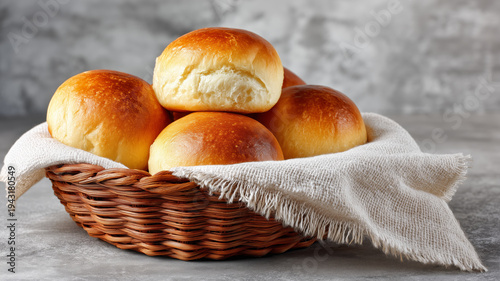 Freshly baked dinner rolls stacked in a basket with a linen napkin 
