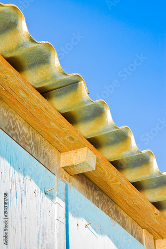 Old aged dangerous roof of a wooden shack made of prefabricated corrugated panels with wooden structure