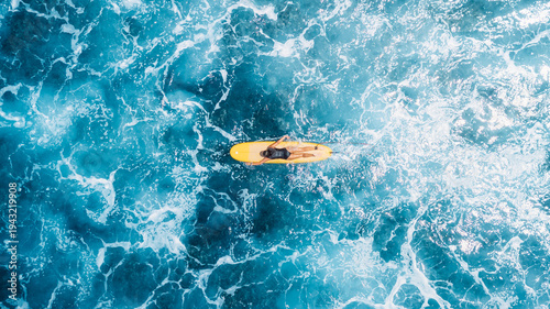 Woman on surfboard in blue ocean. Drone view of surfer during surfing
