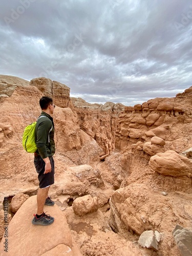 Side view of a male hiker standing on rocks looking at view on an overcast day, Goblin Valley State Park, Emery County, Utah, USA