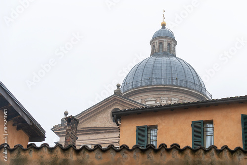 Historic church dome above city rooftops in rainy weather in Reggio Emilia, Italy