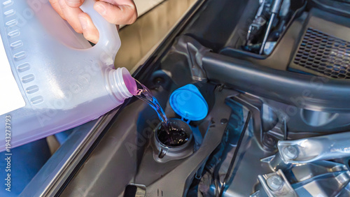 Foto Person pouring windshield washer fluid from a container into a car's reservoir u