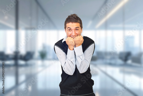 A man in a vest is shaking his hands in a room with a lot of windows