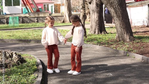 two little twin girls walking in the park in spring