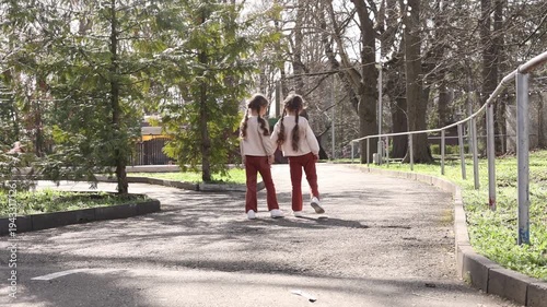 two little twin girls walking in the park in spring