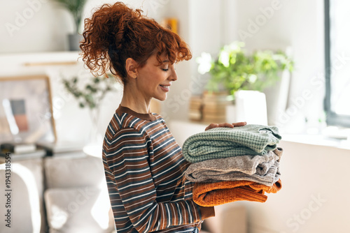 Foto Beautiful mature woman holding clean clothes at home.