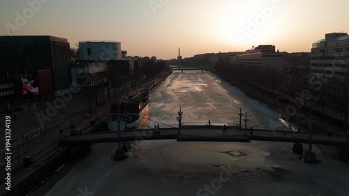Aerial cinematic flight along the frozen Aura River (Aurajoki) at sunset, Turku, Finland.