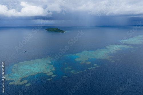 A small ship rests at anchor near a magnificent barrier reef in Fiji's Bligh Channel, east of Viti Levu. This region harbors high marine biodiversity and is a destination for divers and snorkelers.